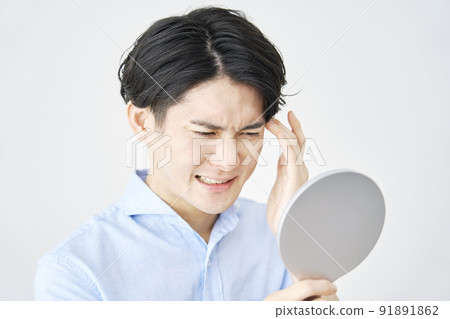 A man checking his eyes with a hand mirror 91891862