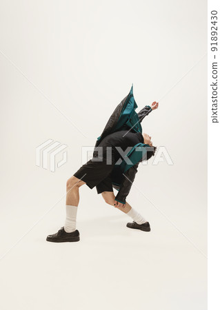 Portrait of stylish young man in black outfit and green coat posing, lying on floor isolated over grey studio background Portrait of stylish young man in black outfit and green coat posing, lying on floor isolated over grey studio background 91892430