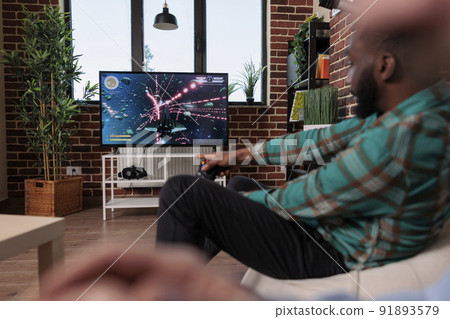 Cheerful man using joystick and console to play video games at home gathering with friends, drinking beer and eating snacks. Group of people having fun with gaming competition, entertainment. 91893579