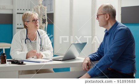 Senior doctor attending consultation with sick patient at appointment in medical office, examining diagnosis for recovery. Checkup visit to find prescription treatment, health care system. 91893688