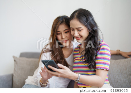 lgbtq, lgbt concept, homosexuality, portrait of two asian women enjoying together and showing love for each other while using smartphone mobile to take selfies. lgbtq, lgbt concept, homosexuality, portrait of two asian women enjoying together and showing love for each other while using smartphone mobile to take selfies. 91895035