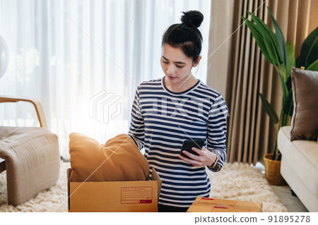 Online merchandising business idea, a beautiful girl is packing pillows in a shipping box to prepare to send items to customers according to orders received from customers Online merchandising business idea, a beautiful girl is packing pillows in a shipping box to prepare to send items to customers according to orders received from customers 91895278