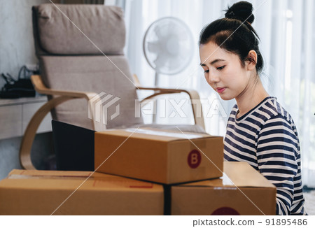 Online merchandising business idea, a beautiful girl is using a computer to insert Track And Trace parcel numbers to customers 91895486