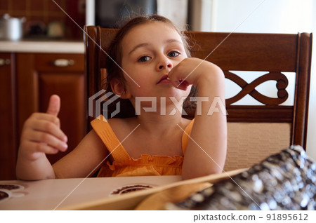 Adorable child girl sitting a dining table with served homemade cherry pie- Monastery hut in the home kitchen interior Adorable child girl sitting a dining table with served homemade cherry pie- Monastery hut in the home kitchen interior 91895612