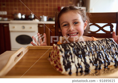 Beautiful and cheerful child, little girl standing at kitchen island and looking at summer sweet homemade cherry pie Beautiful and cheerful child, little girl standing at kitchen island and looking at summer sweet homemade cherry pie 91895615