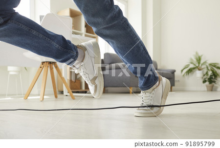 Man or woman falls down after stumbling over an electrical cord on the floor at home Man or woman falls down after stumbling over an electrical cord on the floor at home 91895799