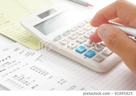 At hand of a person who calculates food expenses with a calculator At hand of a person who calculates food expenses with a calculator 91895825