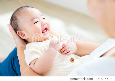 2 個月大的嬰兒在媽媽的腿上大笑 91896388