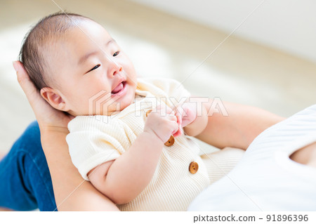 媽媽腿上的接觸，一個微笑的 2 個月大的嬰兒 91896396