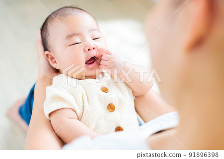 Contact on mom's lap, touching her face, pointing at a 2-month-old baby 91896398