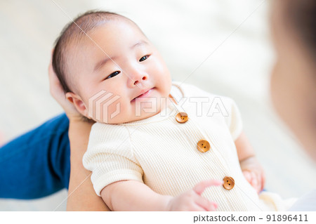 媽媽腿上的接觸，一個微笑的 2 個月大的嬰兒 91896411