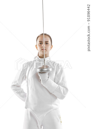 Young girl, fencer in white fencing costume posing with rapier isolated on white background. Sport, youth, hobbies, achievements, goal. 91896442