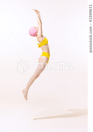 Portrait of young woman in swimming suit and cap jumping into water isolated over grey studio background Portrait of young woman in swimming suit and cap jumping into water isolated over grey studio background 91899631
