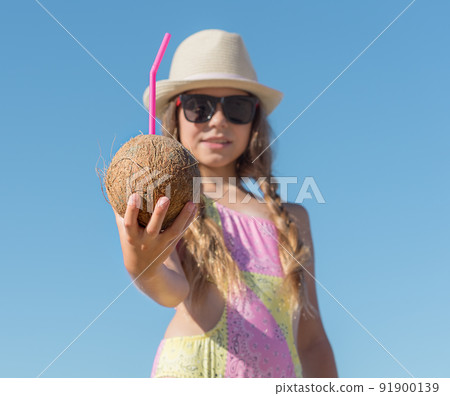 Girl Stretches out her hand with a coconut and a tube against the background of the sky 91900139