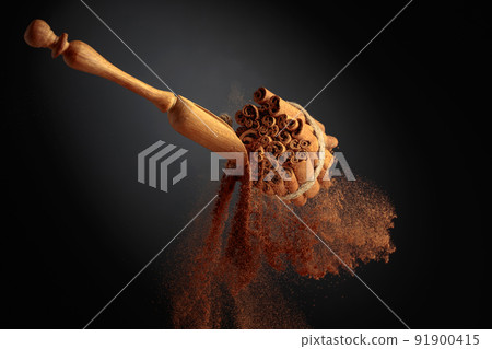 Cinnamon powder is poured out of the wooden spoon. 91900415