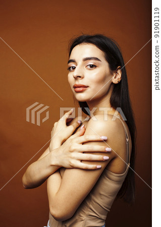 Cute happy young indian woman on brown background in studio close up smiling, fashion beauty warm tanned 91901119