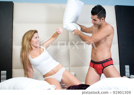 couple in love playing on their bedroom bed at a pillow battle couple in love playing on their bedroom bed at a pillow battle 91901309