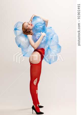 Girl with bright makeup in red torn tights posing with plastic bags with water isolated over grey background. Weirdness. 91901491