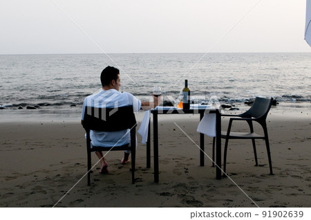 Young man dressed in white waiting to celebrate a romantic dinner on the beach 91902639