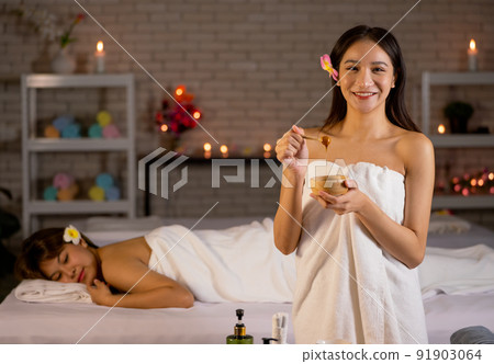 Asian beautiful woman wearing a towel stand in front of other woman lie on bed 91903064