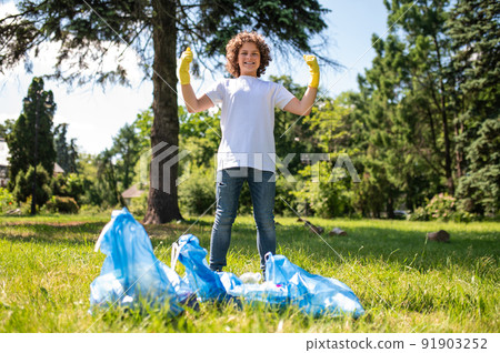 Confident teen standing near bags full with garbage Confident teen standing near bags full with garbage 91903252