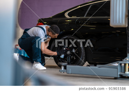 Auto repair worker checking the wheel of the car Auto repair worker checking the wheel of the car 91903386