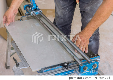 Using manual tools equipment, a construction worker cuts the ceramic tile using manual tools for laying ceramic tiles 91904771