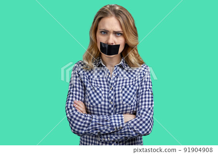 Female protestor with black tape over her mouth demonstrating protest on color background. Female protestor with black tape over her mouth demonstrating protest on color background. 91904908