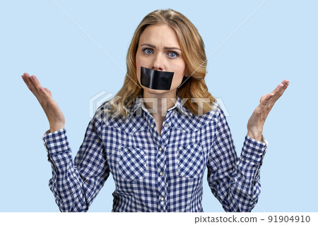 Female protestor with black tape over her mouth demonstrating protest standing on color background. 91904910