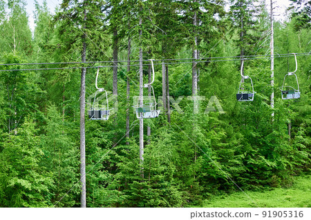 Open cable car line. Karpacz resort in Poland with lift road. Chairlift against green forest trees. Family outdoor recreation in mountains 91905316