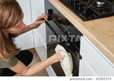 Woman clean electric oven door in kitchen, Housework and maintenance of household appliances concept 91905374