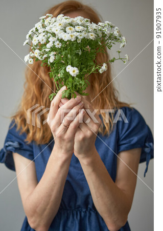 faceless red-haired woman in a blue dress covers her face with white faceless red-haired woman in a blue dress covers her face with white 91907935
