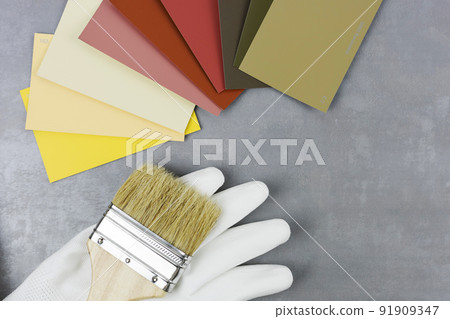 A brush with a wooden handle and paint samples on a gray background. The choice of paint color A brush with a wooden handle and paint samples on a gray background. The choice of paint color 91909347