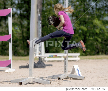 Girl jumping on hobby horse. Equestrian sport. Jumping competition. Champion. Horse sport 91912197