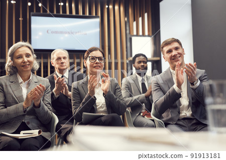 Group of cheerful multi-ethnic business conference participants sitting in conference room and applauding speaker after great presentation Group of cheerful multi-ethnic business conference participants sitting in conference room and applauding speaker after great presentation 91913181