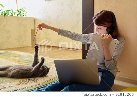 Preteen girl studying at home using laptop along with cat Preteen girl studying at home using laptop along with cat 91913206