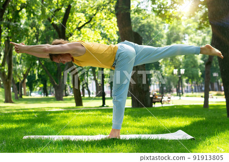Young man practice yoga in the park. Yoga asanas in city park, sunny day. Concept of meditation, wellbeing and healthy lifestyle Young man practice yoga in the park. Yoga asanas in city park, sunny day. Concept of meditation, wellbeing and healthy lifestyle 91913805