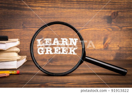 Learn Greek. Magnifying glass and textbooks on wooden background Learn Greek. Magnifying glass and textbooks on wooden background 91913822