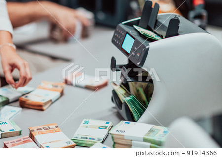 Bank employees using money counting machine while sorting and counting paper banknotes inside bank vault. Large amounts of money in the bank Bank employees using money counting machine while sorting and counting paper banknotes inside bank vault. Large amounts of money in the bank 91914366