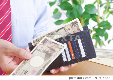 一個穿襯衫的男人從錢包裡拿出一萬日元的鈔票 91915852