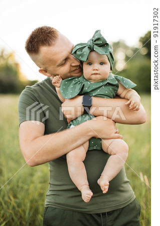 Portrait of happy father in green t-shirt kissing cheek of his little daughter Portrait of happy father in green t-shirt kissing cheek of his little daughter 91917302