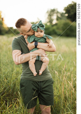 Portrait of happy father in green t-shirt kissing cheek of his little daughter Portrait of happy father in green t-shirt kissing cheek of his little daughter 91917309
