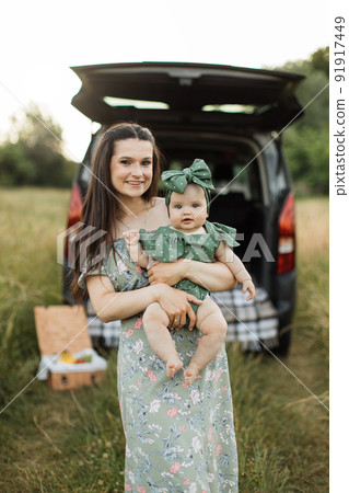 Young single mother holding on hands her little daughte,r standing on the grass during a picnic 91917449