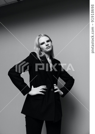 The middle portrait with the legs of a professional model in a classic suit posing with both hands on the waist m looks into the camera The middle portrait with the legs of a professional model in a classic suit posing with both hands on the waist m looks into the camera 91918698