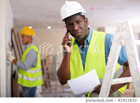 Man builder having telephone conversation in construction site Man builder having telephone conversation in construction site 91922630