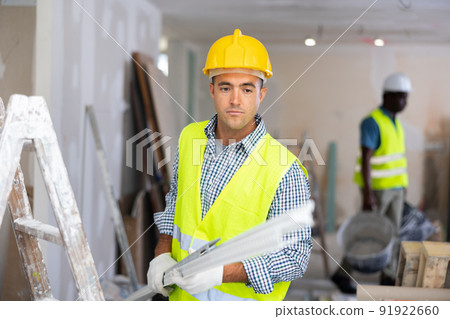 Man builder carrying metallic profile while working in construction site closeup 91922660