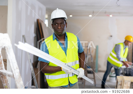 African-american man builder carrying metallic profile while working in construction site closeup African-american man builder carrying metallic profile while working in construction site closeup 91922686