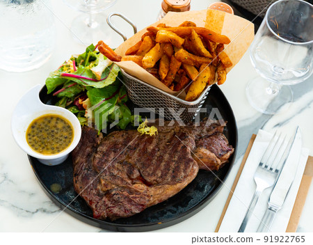 Beef entrecote with French fries, fresh greens and sauce with capers Beef entrecote with French fries, fresh greens and sauce with capers 91922765