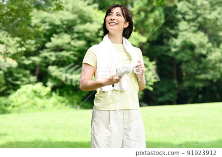 一個女人在樹蔭下使用風扇 91923912