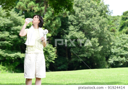 Woman hydrating in the shade of a tree 91924414